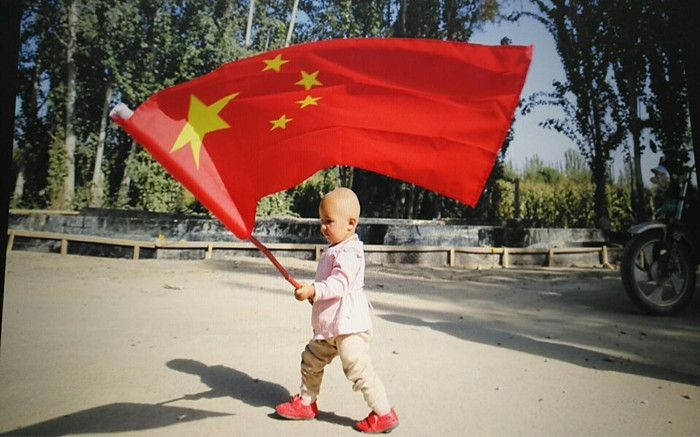 9月29日，自治区人民政府办公厅干部刘长缨和她在喀什地区疏勒县阿拉力乡马木克村3组的结亲户尤努斯·斯马义一家在新盖的富民安居房前挂国旗，共同给祖母亲过生日。2_副本_副本.jpg